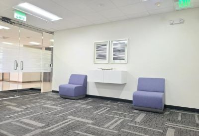 Seating nook with two purple armchairs and modern abstract wall art.