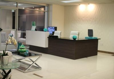 Modern reception desk with white and dark wood finishes and stylish green decorative accents.