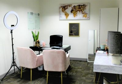 Private office with pink velvet chairs and a ring light for content creation.