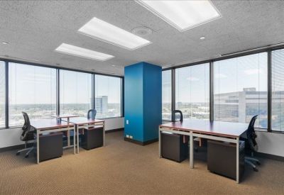 Spacious corner office with three desks, blue accent pillar, and expansive city views.