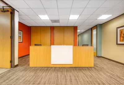Reception area with a light wood desk and warm orange accent wall.