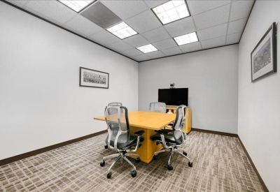 Small private meeting room with a wooden table and video conferencing screen.
