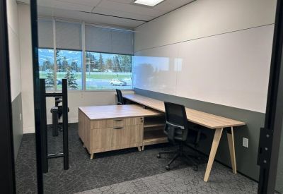 Private office featuring a wooden desk, storage unit, and large window.
