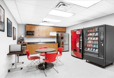 Kitchen and break area featuring vending machines and bright red chairs.