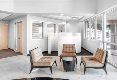 Reception lobby area with comfortable armchairs and a glass wall.
