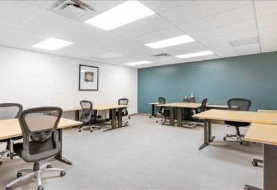 Spacious open-plan office with multiple workstations and a teal feature wall.