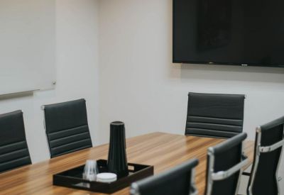 Professional conference room with a wooden table and large wall-mounted monitor.