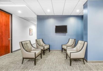 Casual waiting area with four grey armchairs and a blue accent wall.