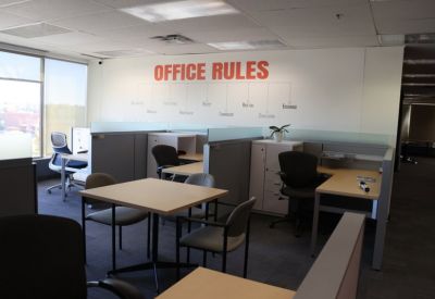 Collaborative workspace featuring an Office Rules wall mural and several open workstations.
