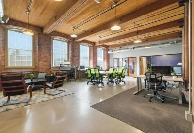 Spacious open-plan office with exposed brick walls, timber ceilings, and industrial lighting.
