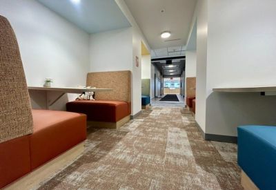 Cozy seating booths with orange upholstery in a brightly lit hallway area.