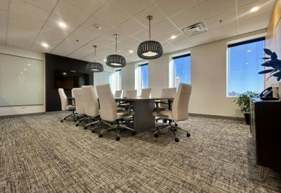 Spacious boardroom featuring a large table, white leather chairs, and modern pendant lighting.