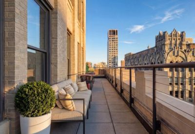 Sunlit outdoor terrace with comfortable sofa seating and views of historic city architecture.