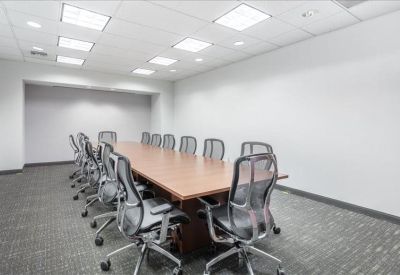 Spacious boardroom with a long wood table and grey mesh chairs.