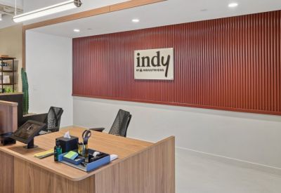 Modern wooden reception desk against a textured terracotta feature wall with branding.