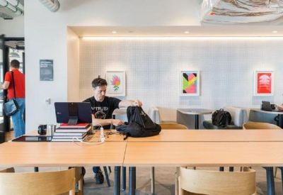 Spacious open-plan office with wooden desks and shared workspaces.