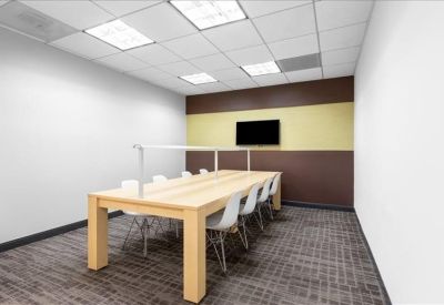 Long communal work table with overhead task lighting and built-in screen.