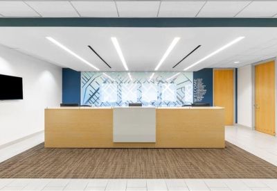 Professional reception area with a light wood desk and patterned wall graphic.