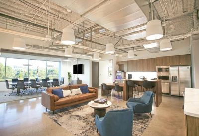 Communal lounge and kitchen area with blue armchairs, a leather sofa, and a breakfast bar.