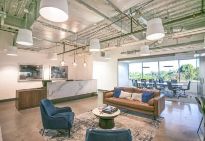 Reception area featuring a marble desk, leather sofa, and industrial ceiling with modern pendant lights.