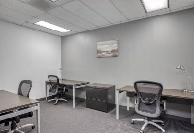 Brightly lit three-person private office with grey walls and ergonomic chairs.