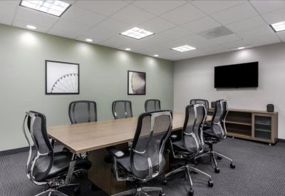 Professional meeting room with a long wooden table and grey mesh chairs.