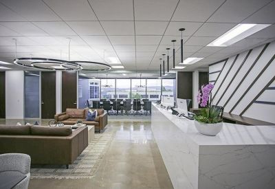 Modern reception area featuring a white marble desk, leather sofas, and geometric wall patterns.
