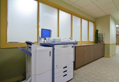 Office document center with a large multi-function printer and built-in wood cabinetry.