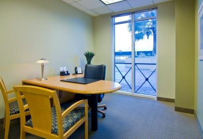 Private office suite with a wood desk, guest chairs, and natural light from a large window.