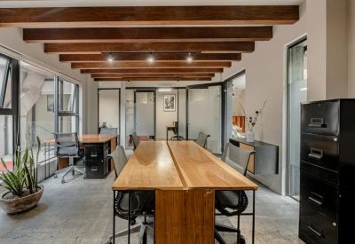 Office workspace featuring a long wooden desk and industrial ceiling beams.