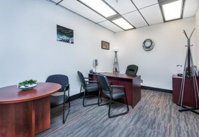 Private executive office with a round dark wood table and matching desk.
