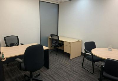 Small office room with two light-colored desks and ergonomic mesh chairs.