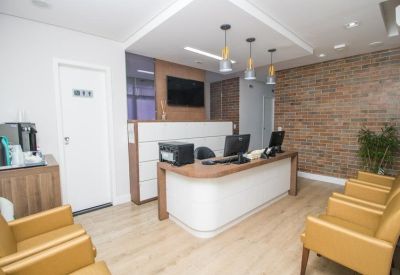 Reception area with a white front desk, brick accent wall, and gold-colored waiting chairs.