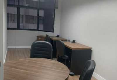 Private office featuring a round wooden table and secondary workstations by the window.