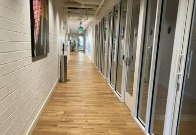 Long corridor with wooden flooring and glass office doors.