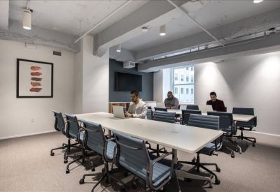 Large conference room with a long white table, blue chairs, and a flat-screen display.