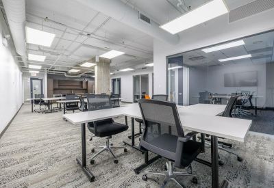 Open-plan office with white desks, ergonomic chairs, and glass partitions.