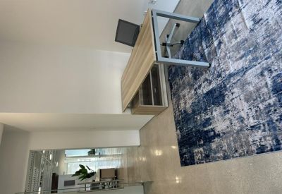 Private office with a light wood desk, blue patterned rug, and glass partitions.