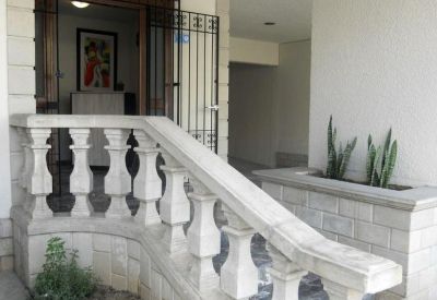 Building entrance with white stone balustrades and a gated doorway.