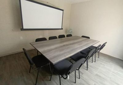 Meeting room with large projection screen and gray wood-grain conference table.