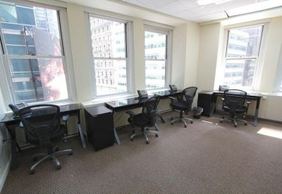 Bright office space with multiple workstations and large windows overlooking the city.