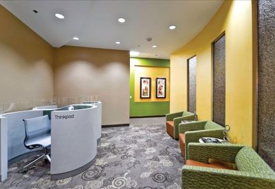 Modern reception lobby with curved white desks and green lounge chairs.