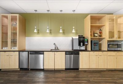 Modern office kitchen with wooden cabinetry and stainless steel appliances.
