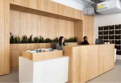 Light wood reception desk featuring a green plant wall and mail slots.