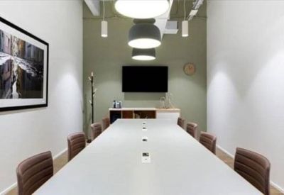 Long modern conference room with a white table and black-and-white wall art.