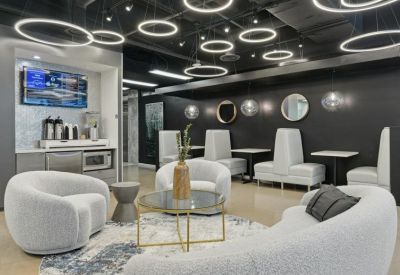 Modern lounge with white curved armchairs and circular halo pendant lights.