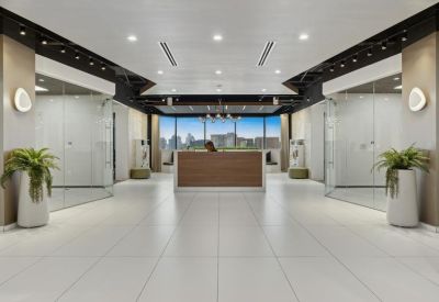 Bright reception lobby featuring a wooden front desk and glass-walled suites.