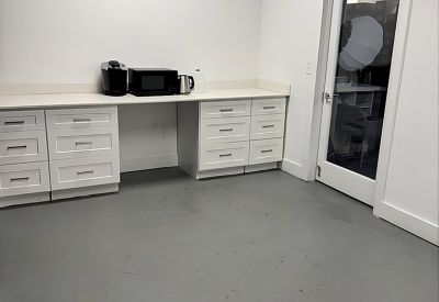 Bright kitchenette area with white cabinetry, microwave, and coffee maker.