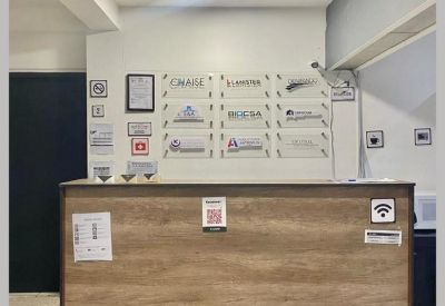 Reception area featuring a wood-fronted desk and a wall with various business logos.