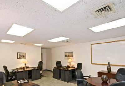 Spacious shared workspace featuring multiple workstations and a large whiteboard.